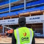 Qwik Security guard in a high-visibility vest with Kane construction signage and building works in the background