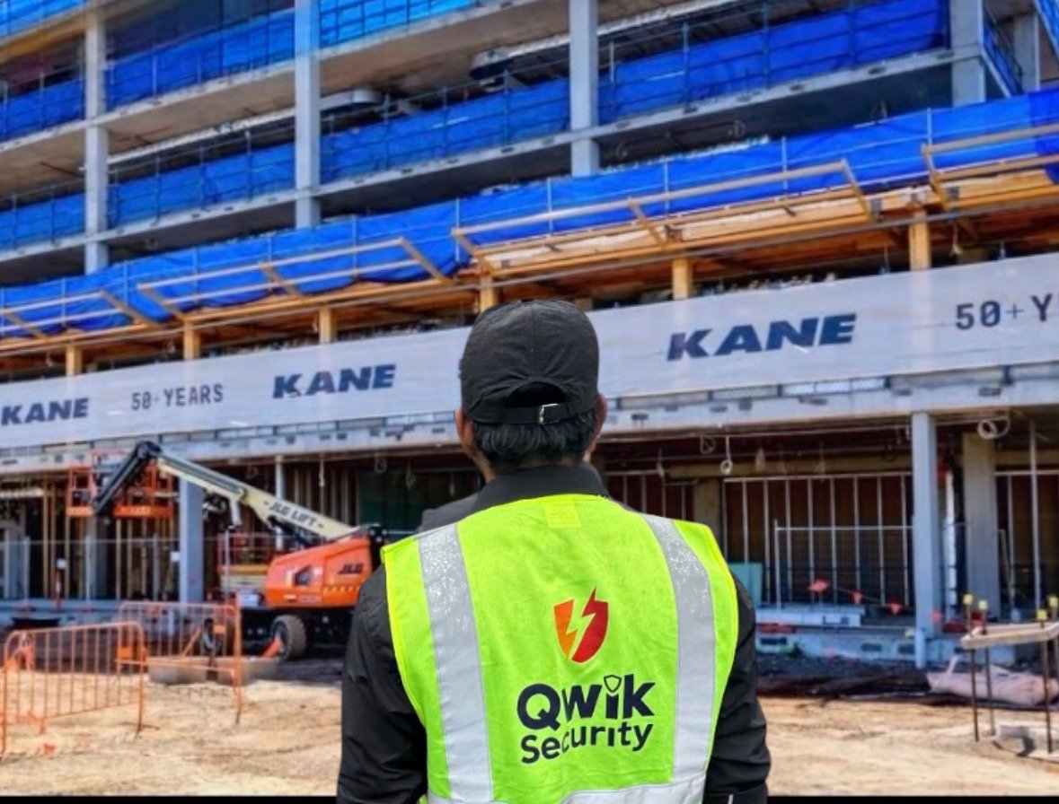 Qwik Security guard in a high-visibility vest with Kane construction signage and building works in the background