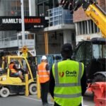 Qwik Security guard at a construction site with Hamilton Marino signage and machinery in the background