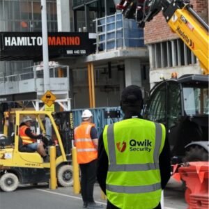 Qwik Security guard at a construction site with Hamilton Marino signage and machinery in the background