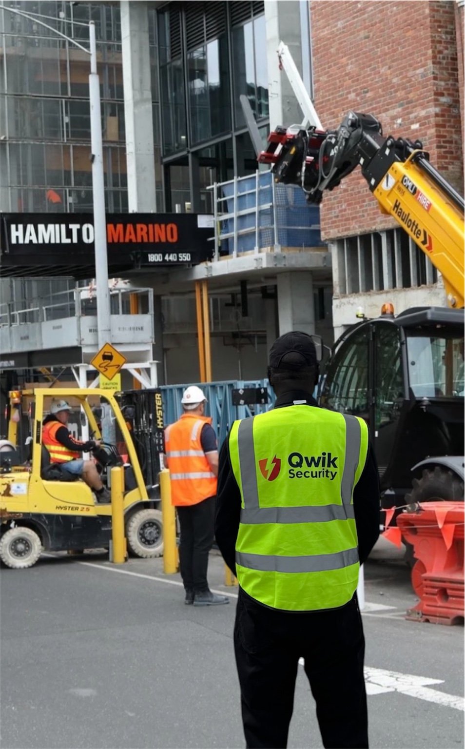 Qwik Security guard at a construction site with Hamilton Marino signage and machinery in the background