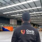 Qwik Security static guard inside a warehouse with forklifts and industrial equipment visible