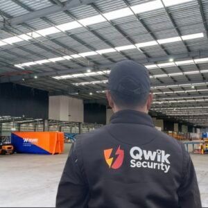 Qwik Security static guard inside a warehouse with forklifts and industrial equipment visible