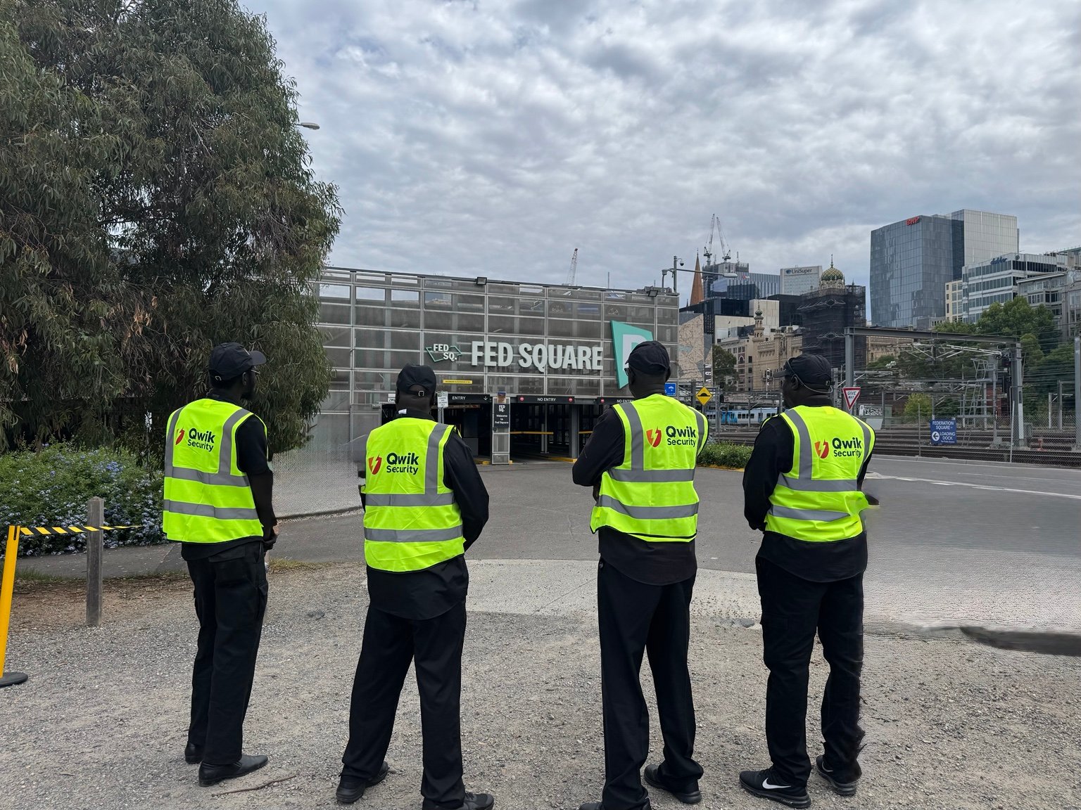 Four Qwik Security event guards in high-visibility vests at Federation Square, Melbourne