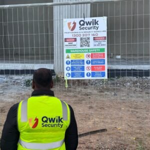 Qwik Security guard in a high-visibility vest at a fenced construction site