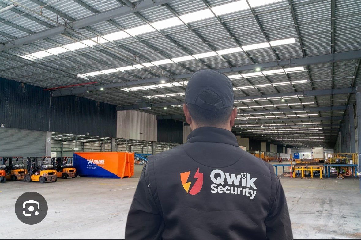 Qwik Security static guard inside a warehouse with forklifts and warehouse operations visible